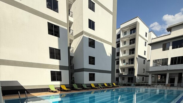 Una piscina con solárium empinado, rodeada de edificios de varios pisos con balcones.