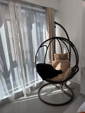 A room with a hanging chair, sheer curtains, and a tiled floor. - Modern Airport Studio Near JKIA, SGR, Nairobi Expy (Syokimau)