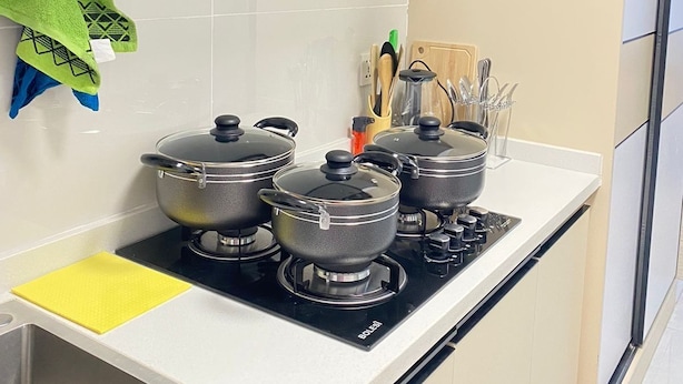 A kitchen with a stove, pots, and a range hood.
