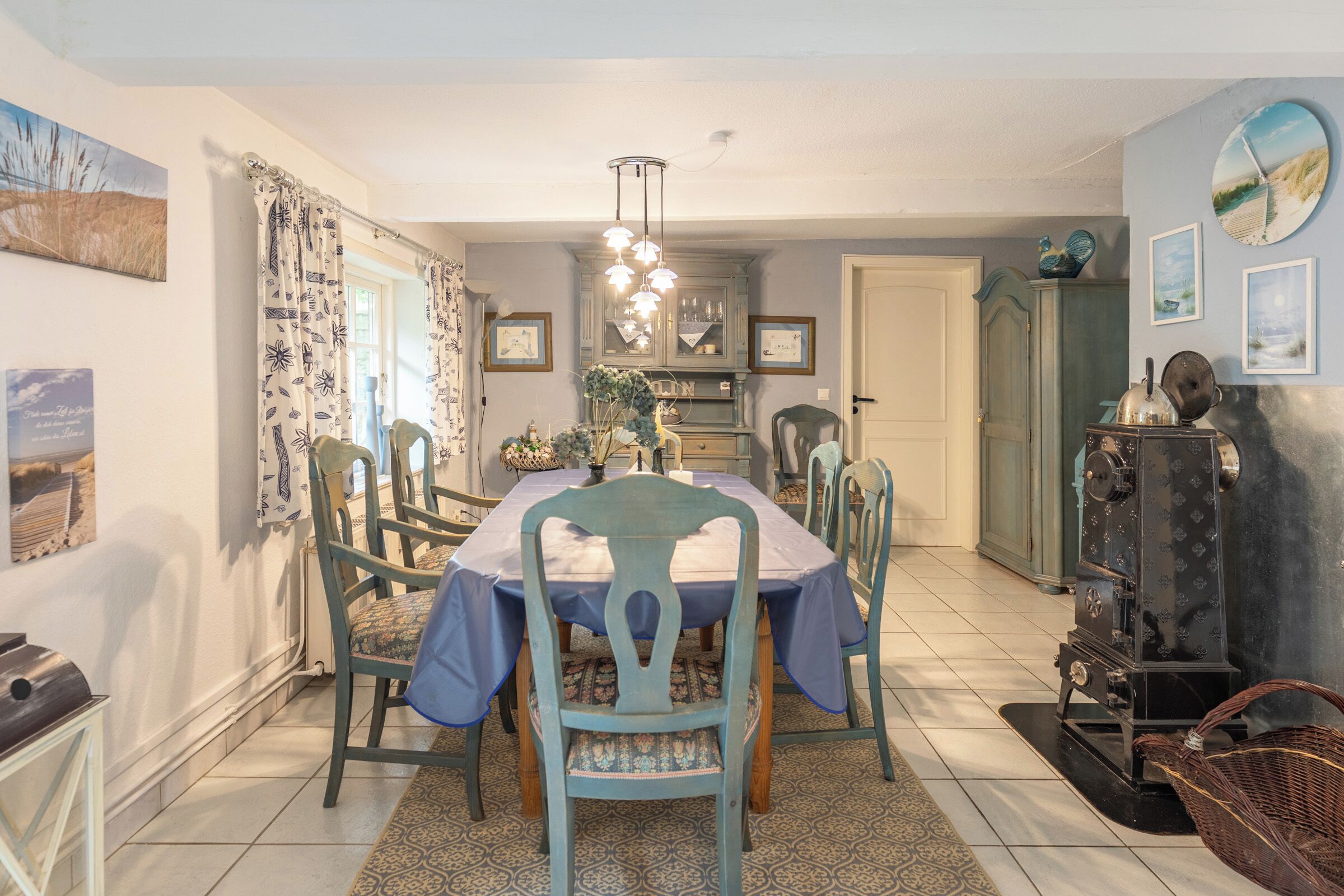 A dining area with a table set for four, surrounded by chairs. A vintage stove is visible to the right.