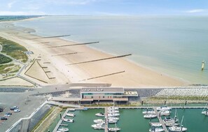 An aerial view of a coastal area with a beach, a marina with boats, and a building with a modern design. - 2 bedroom beautiful apartment in Cadzand (Cadzand)