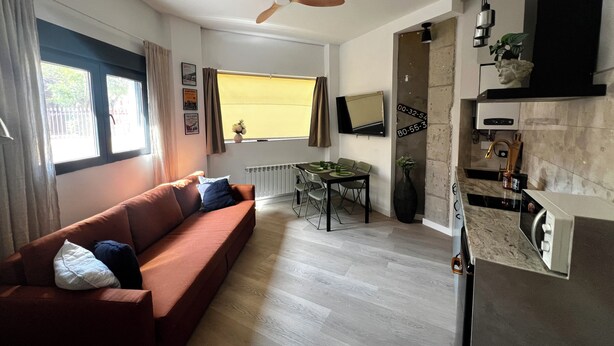 A modern living room with a sofa, dining table, and kitchen area. - La Arquita, tu apartamento en Valladolid (Valladolid)