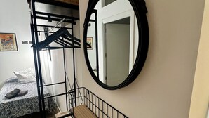 Et sovesalværelse med køjesenge, et rundt spejl og en træhylde.