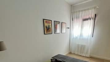 Un dormitorio con cama, almohadas, una esterilla de yoga y tres cuadros en la pared.