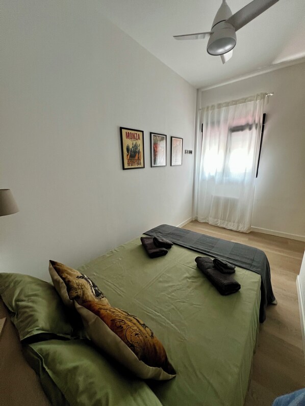 A bedroom with a bed, pillows, a yoga mat, and three framed pictures on the wall.