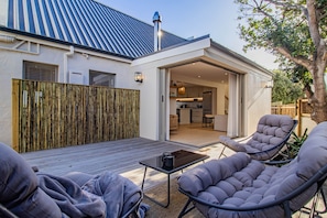Une terrasse extérieure avec une table et des chaises, une clôture en bois et un bâtiment au design moderne.