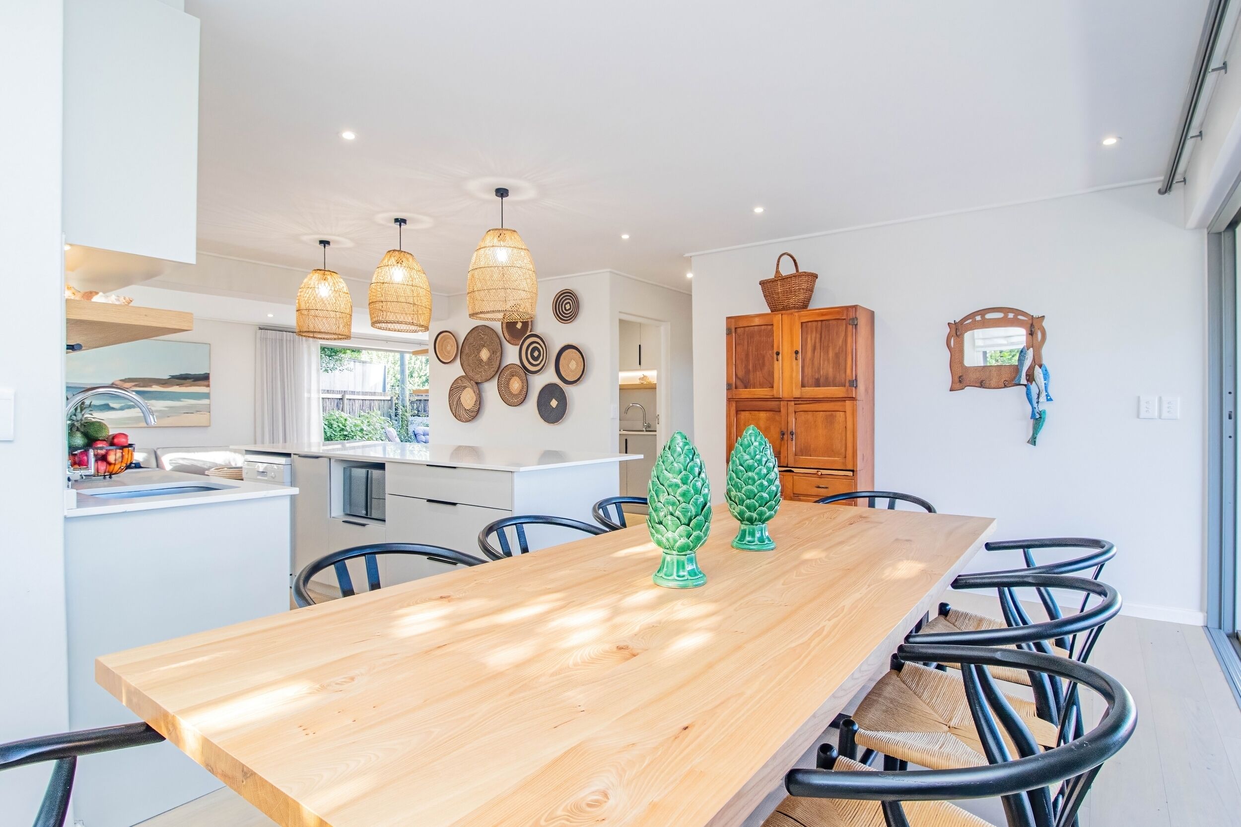 A modern kitchen with a wooden dining table, black chairs, and decorative wall art.