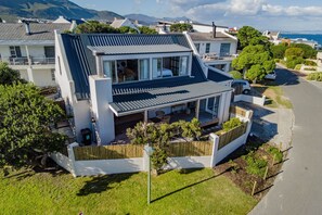 A modern house with a sloped roof, a balcony, and a garden area.