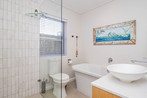 A bathroom with a toilet, bathtub, and a large white sink. - Pikkewyntjie | Sea view | Small families (Vermont)