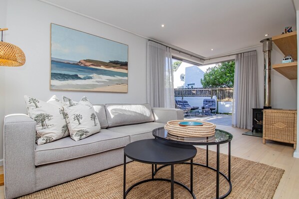 Ein modernes Wohnzimmer mit einer Couch, einem runden Couchtisch und einem Bild mit einer Strandansicht.