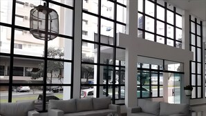 Una habitación amplia con ventanas grandes, un conjunto de sofá moderno y una mesa de centro de vidrio.