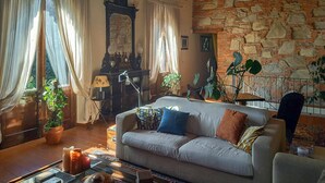 A cozy living room with a stone wall, a piano, and a sofa with cushions. - 4 bedroom awesome home in Quiesa (Quiesa)