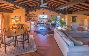 A spacious living room with a high ceiling, a fireplace, a dining area with a table and chairs, and a cozy seating area with a sofa and armchairs.