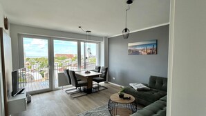 A modern living room with a balcony, a dining area, and a sofa. - Seaside 53° FeWo 7 - Apartment close to the beach with sea view and balcony in (Cuxhaven)