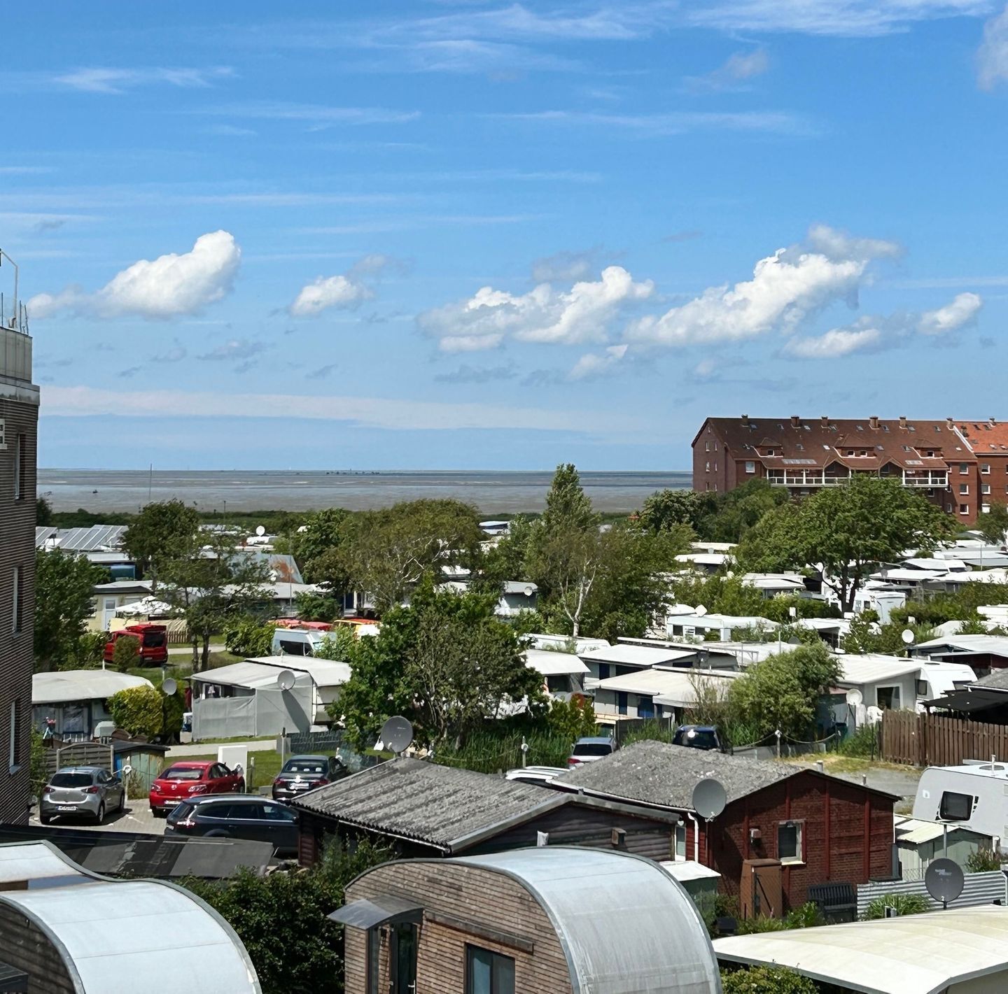 A caravan park with multiple caravans, a few buildings, and a view of the sea.