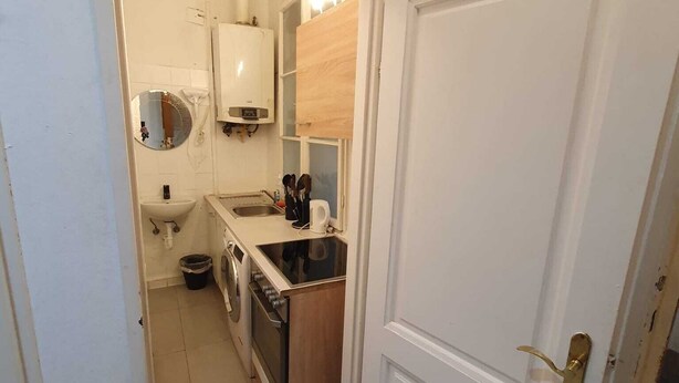A narrow kitchen with a sink, stove, and a small countertop. - Modern 2BR Apt Near Karlsplatz (Vienna)