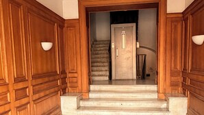 A hotel entrance with wooden paneling, marble flooring, and a red carpet leading to a staircase. - Vatican Gold Medals (Roma)