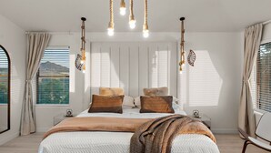 A bedroom with a large bed, two bedside tables, a hanging light fixture, and a window with blinds.