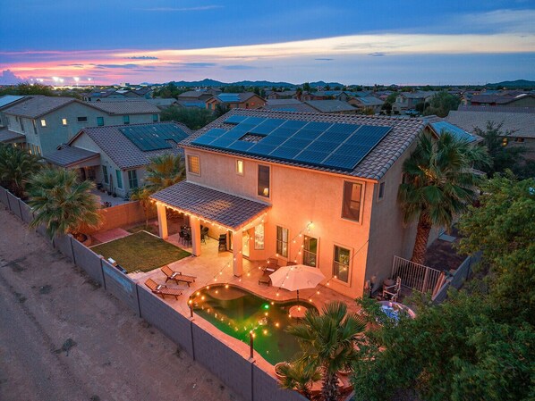 A two-story house with a swimming pool, solar panels, and a covered patio area.