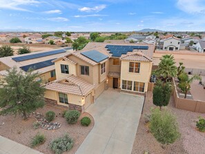 A residential property with a spacious driveway, solar panels on the roof, and a well-maintained garden.