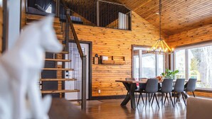 Un intérieur moderne avec un plafond en bois, un coin repas comprenant une table et des chaises, et un escalier menant à un niveau supérieur.