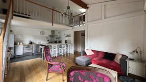 A spacious living area with a high ceiling, a dining area with a kitchen in the background, and a staircase leading to an upper level. - Gd appartement cozy 85 M2 2chb + grande mezzanine accès funiculaire les arcs (Bourg-Saint-Maurice)