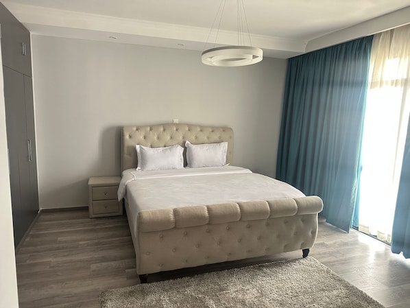 Une chambre à coucher moderne avec un grand lit, une table de chevet, une armoire et un luminaire suspendu.