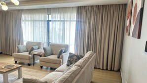 A modern living room with a sofa, armchairs, a coffee table, and a large window with curtains. - Spacious 5-bedroom apartment in terrific Nairobi -White Oak Residency with AC, (Nairobi)