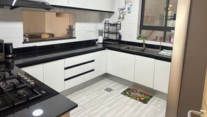 A modern kitchen with white cabinets, black countertops, a stainless steel range hood, a built-in oven, and a window with a view. - Spacious 5-bedroom apartment in terrific Nairobi -White Oak Residency with AC, (Nairobi)