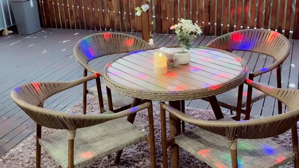 A covered outdoor patio with a round table and four wicker chairs, a small potted plant, and a candle. - “Private Bedroom & Large Deck + Separate Entrance” (Papatoetoe)
