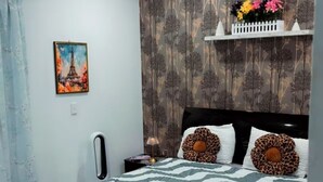 A bedroom with a bed, a nightstand, a wall-mounted air conditioner, a painting, and a curtain. - “Private Bedroom & Large Deck + Separate Entrance” (Papatoetoe)