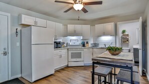 Une cuisine moderne avec des armoires blanches, un four encastré et un ventilateur de plafond.