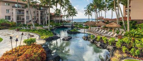 A resort with a pool, palm trees, and a view of the ocean.