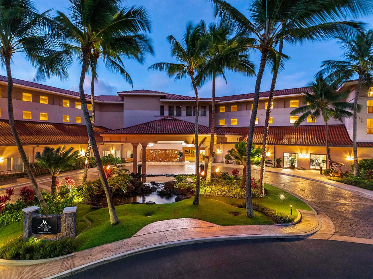 A resort with a central courtyard, palm trees, and a swimming pool.