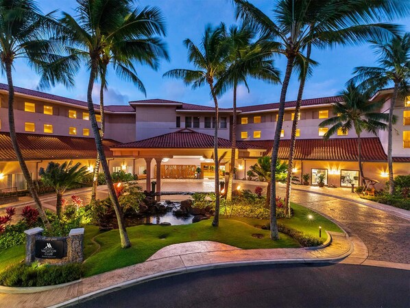 A resort with a central courtyard, palm trees, and a swimming pool.