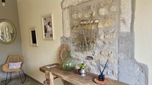 A rustic interior with a stone wall, a wooden bench, a wicker chair, and a mirror.