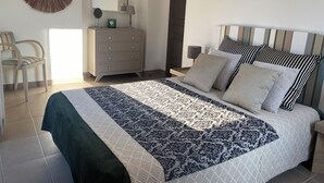 A bedroom with a bed, a dresser, a chair, a mirror, and a door.