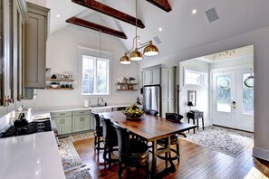 A spacious kitchen with a large island, wooden flooring, and a dining area with a wooden table and chairs.