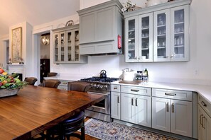 A kitchen with a wooden table, cabinets, and a stove.