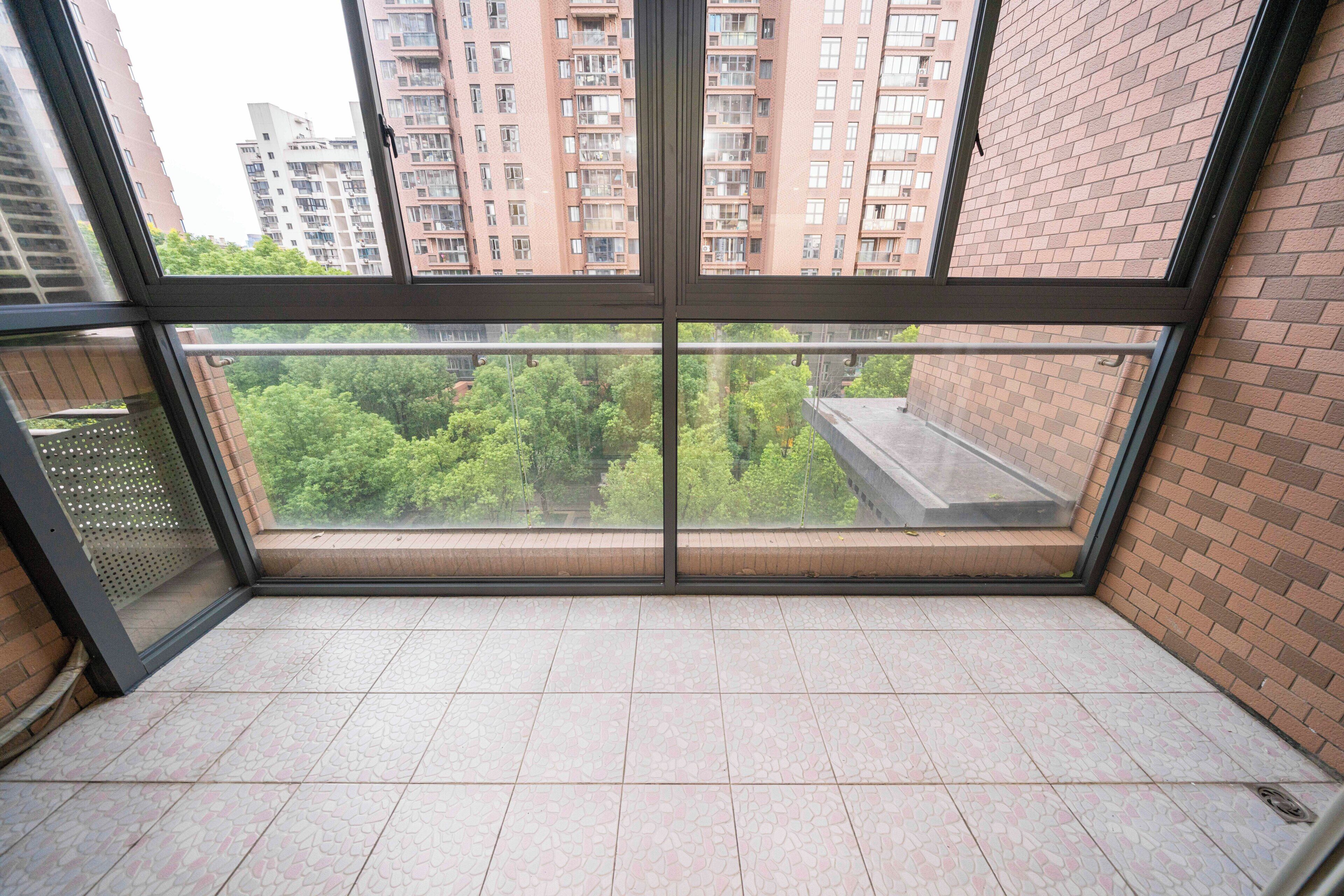 Een balkon met uitzicht op een bakstenen gebouw en bomen.