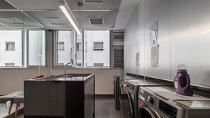 A modern laundry room with a marble sink, stacked washers and dryers, and a large window providing natural light. - Frei215 in S o Paulo (São Paulo)