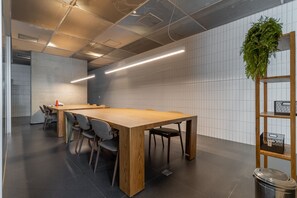 A modern conference room with a long wooden table, grey chairs, a potted plant, and a wooden shelf unit. - Frei215 in S o Paulo (São Paulo)