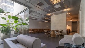 A modern lobby with seating areas, a large plant, and a view of the outside. - Frei215 in S o Paulo (São Paulo)