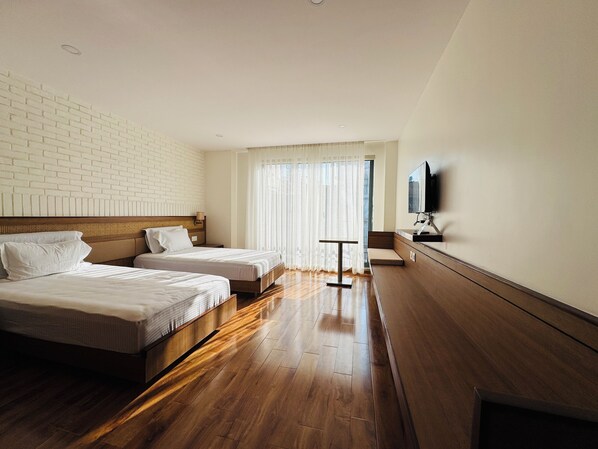 A hotel room with two beds, a TV mounted on the wall, and a large window with sheer curtains. - Navaya Residence (Lalitpur)
