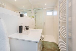 A modern bathroom with a white sink, a glass shower enclosure, and a white towel rack. - Comfortable apartment in Villa Tanneck with terrace near the beach and center (Ahlbeck)