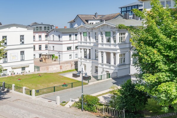 A multi-story building with a central courtyard, a green lawn, and a street in front. - Comfortable apartment in Villa Tanneck with a terrace near the Baltic Sea beach (Ahlbeck)