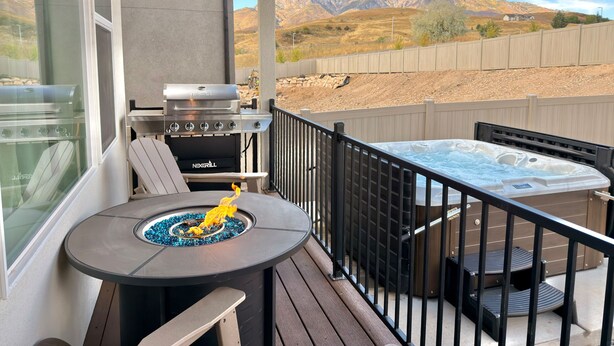 A balcony with a grill, a hot tub, and a view of mountains. - Roam Away From Home R4|Fire Pit |Office |Hot Tub (Mountain Green)