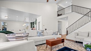 A spacious living room with a high ceiling, a staircase, and a view of the kitchen. - Roam Away From Home R4|Fire Pit |Office |Hot Tub (Mountain Green)