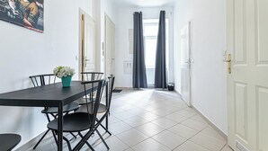 A dining area with a table and chairs, a potted plant, and a painting on the wall. - Comfy 2BR Flat Belvedere Vicinity (Vienna)