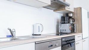 A modern kitchen with a built-in dishwasher, a coffee maker, and a stove. - Comfy 2BR Flat Belvedere Vicinity (Vienna)